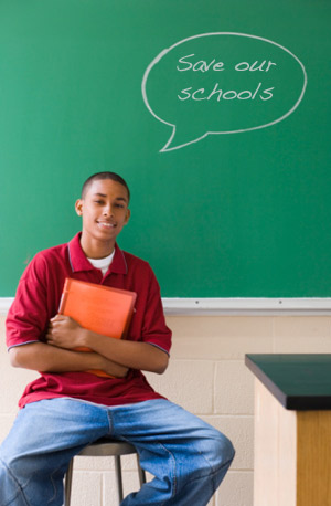 Student writing on chalkboard that we need to save out schools