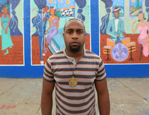 Charles Jean Pierre artist standing in fron of is mural