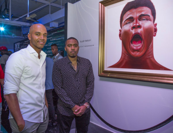 Nas (right) stands with artist and Project Wild Rabbit judge Kadir Nelson (left), beside his painting of the late Muhammad Ali.