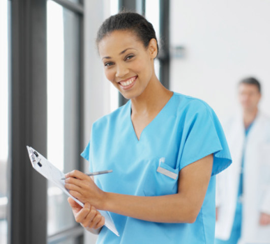 African American nurse smiling while holding medical chart