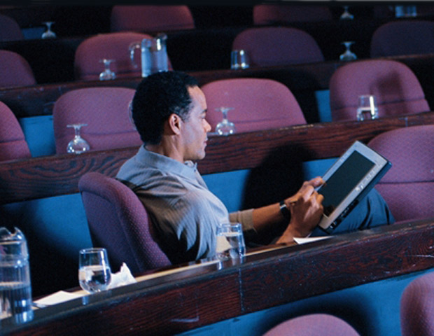 Man using a tablet in empty auditorium