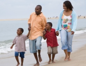 black family walking barefoot along the beach