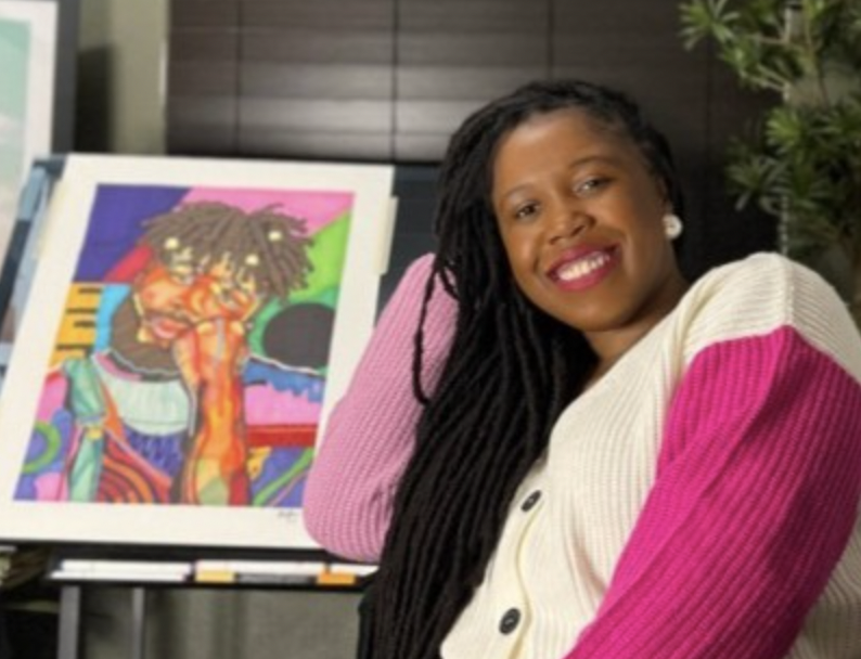 Domonique Brown sitting next to one of her pieces of framed art