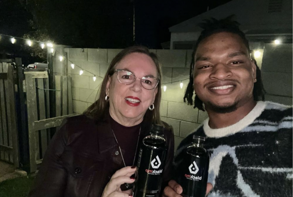 Wanda Dench and Jamal Hinton holding bottles of their black alkaline water