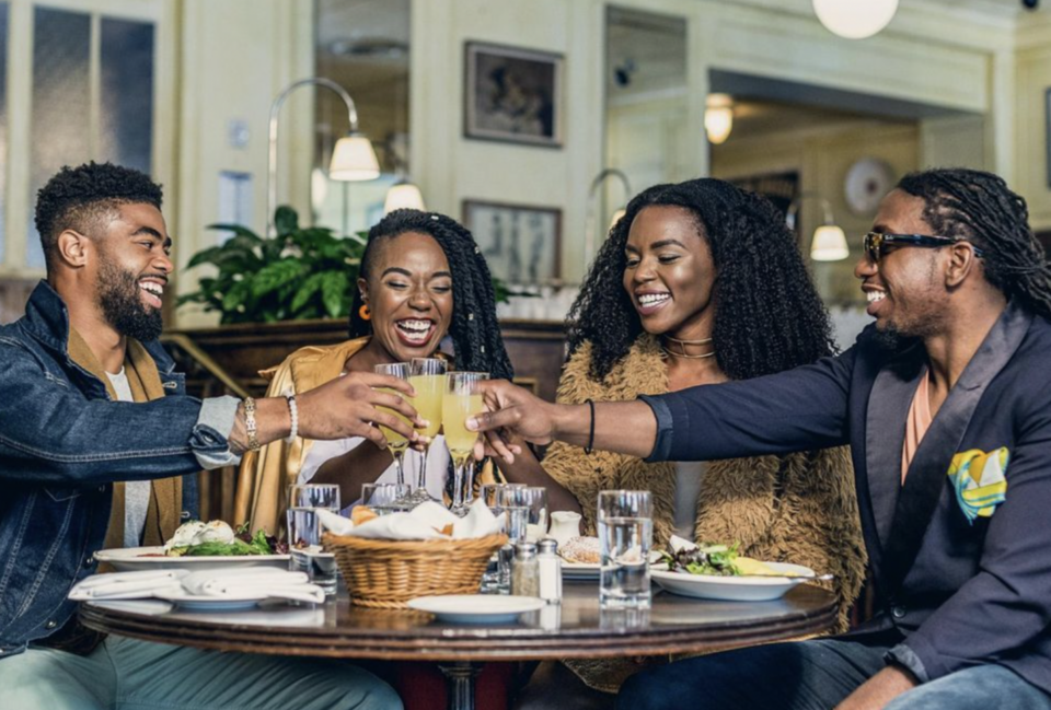 Black men and women making a toast around a table