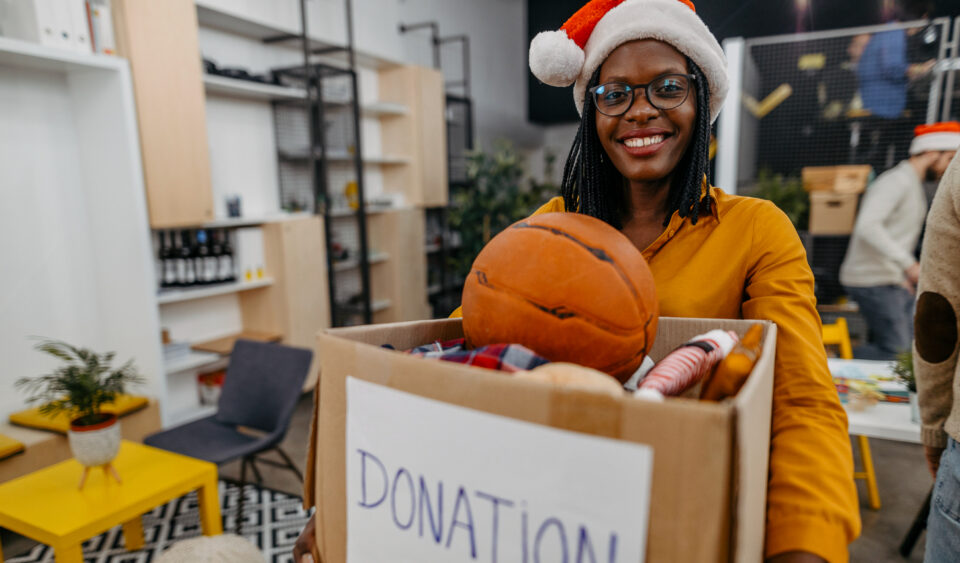 Smiling woman holding full donation box, volunteering at Christmas charity