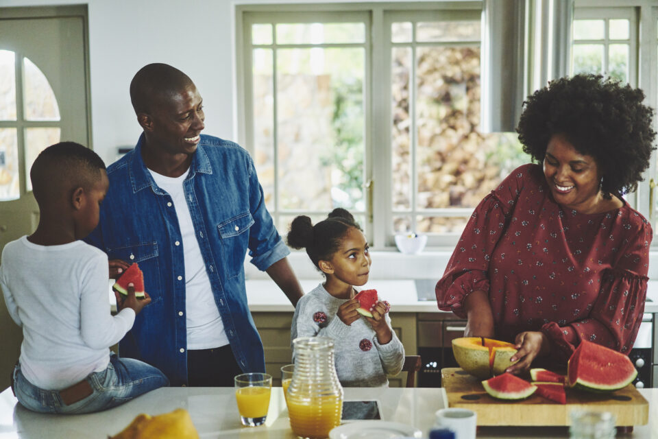 Smiling family eating a healthy snack of watermelon at home