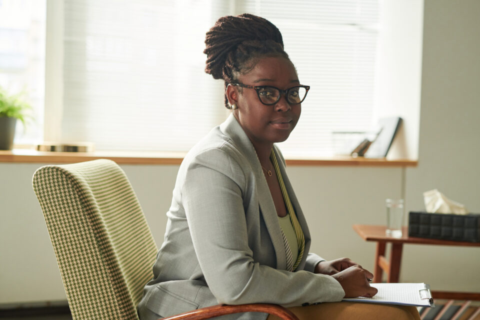 Portrait of African American psychologist in eyeglasses sitting on armchair